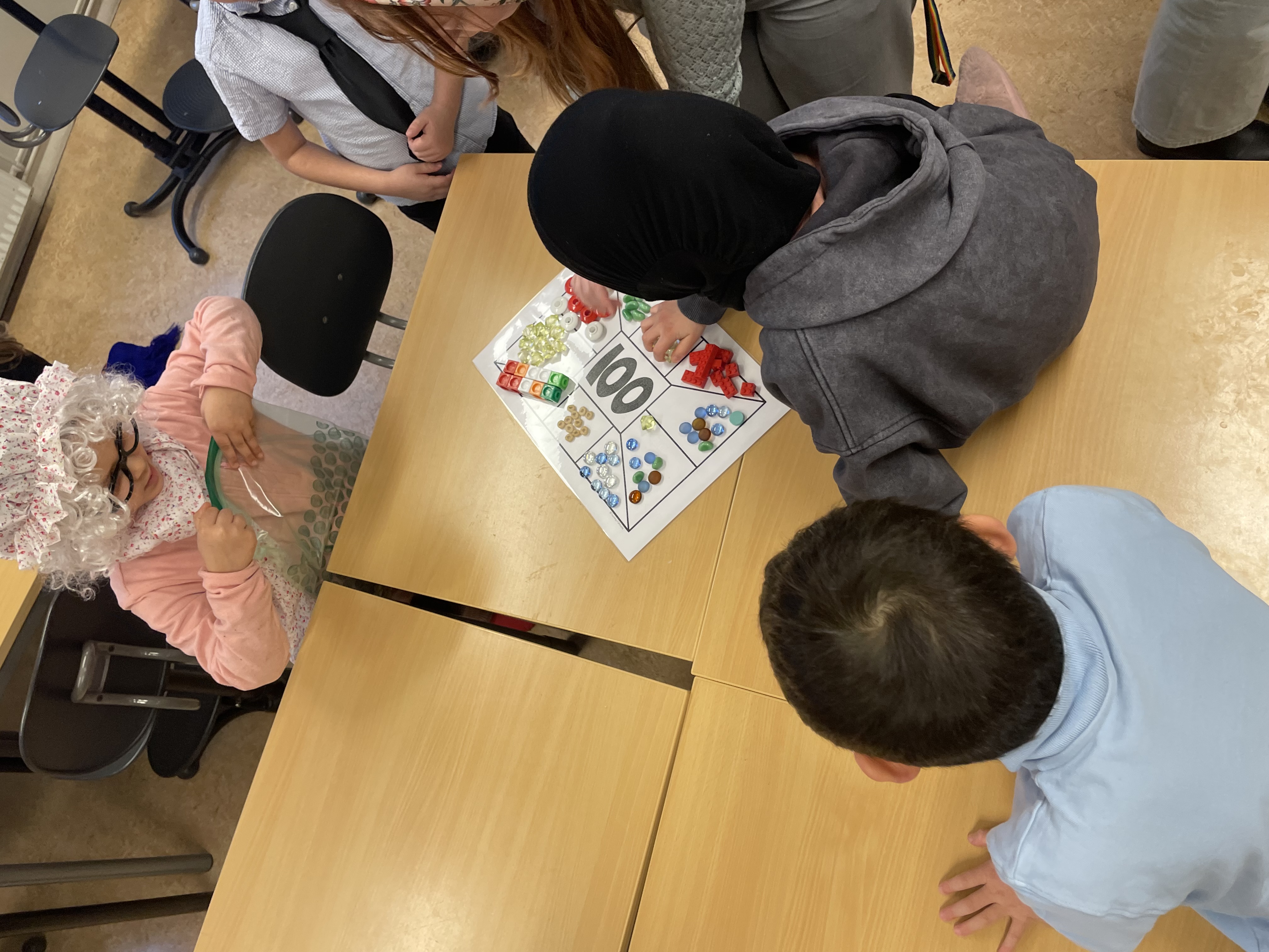 en gruppe barn som sitter rundt et bord med en person i et plagg