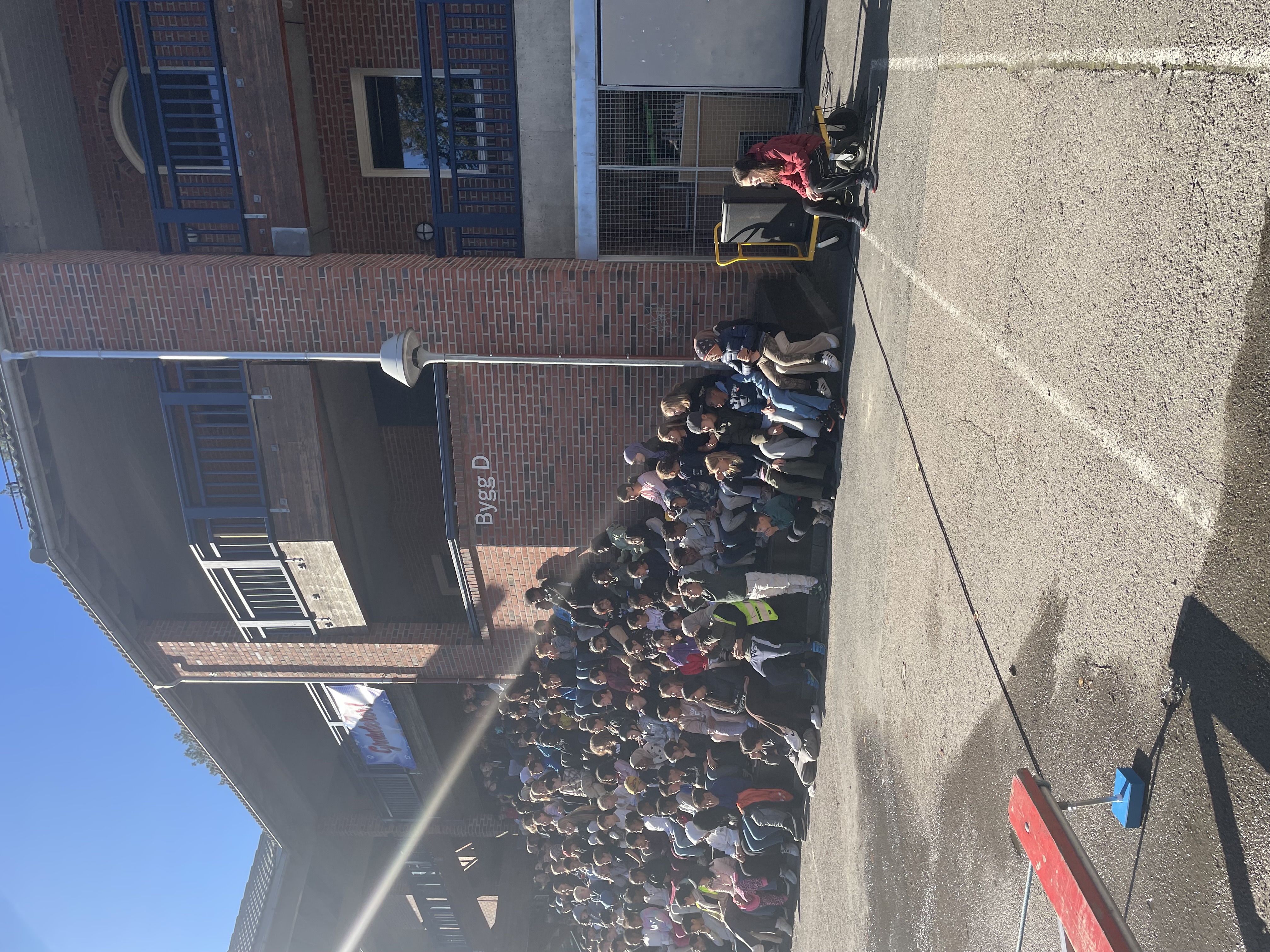 en gruppe mennesker som sitter på en benk foran en bygning