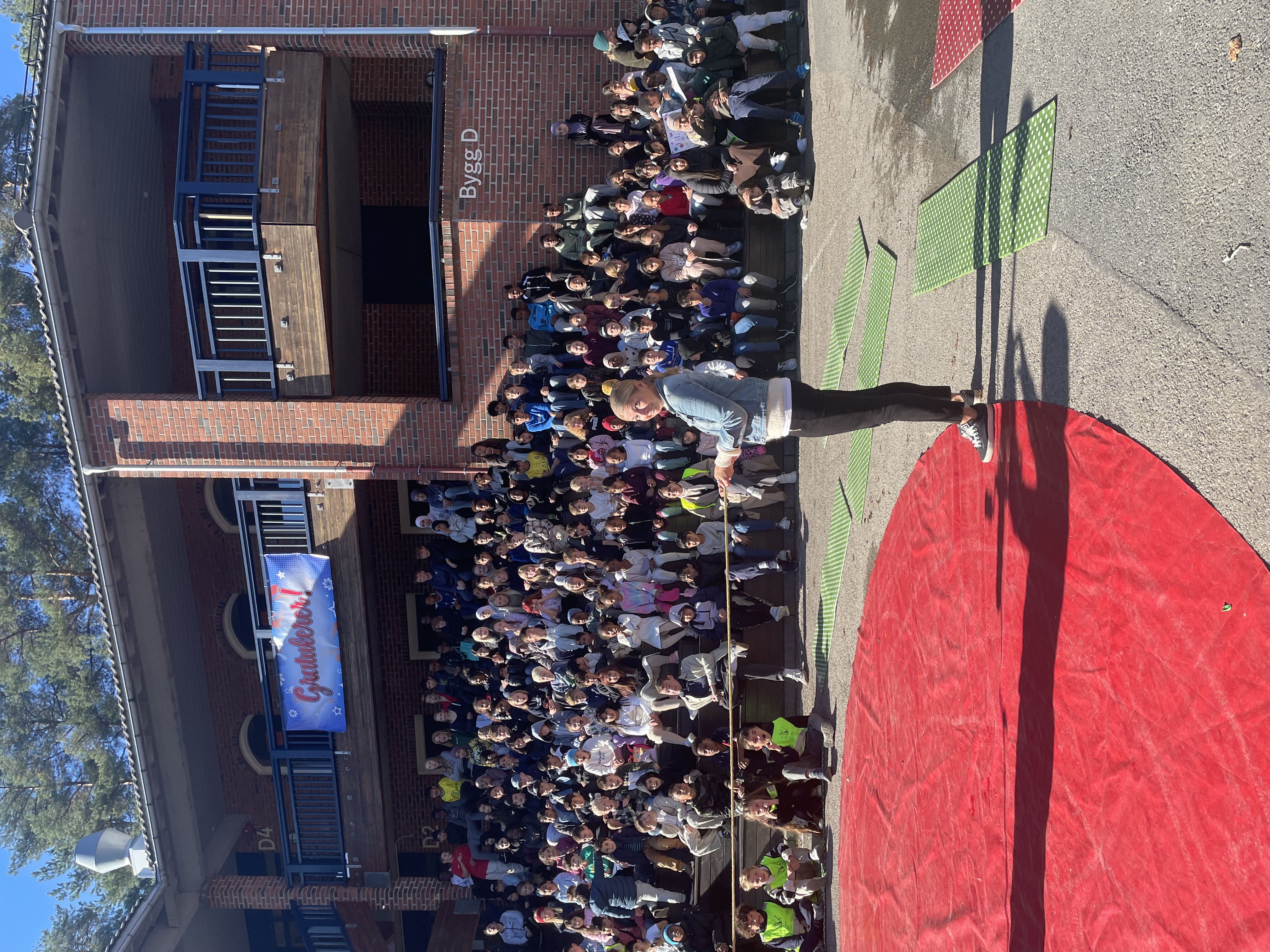 en gruppe mennesker som står på en gate med en bygning i bakgrunnen