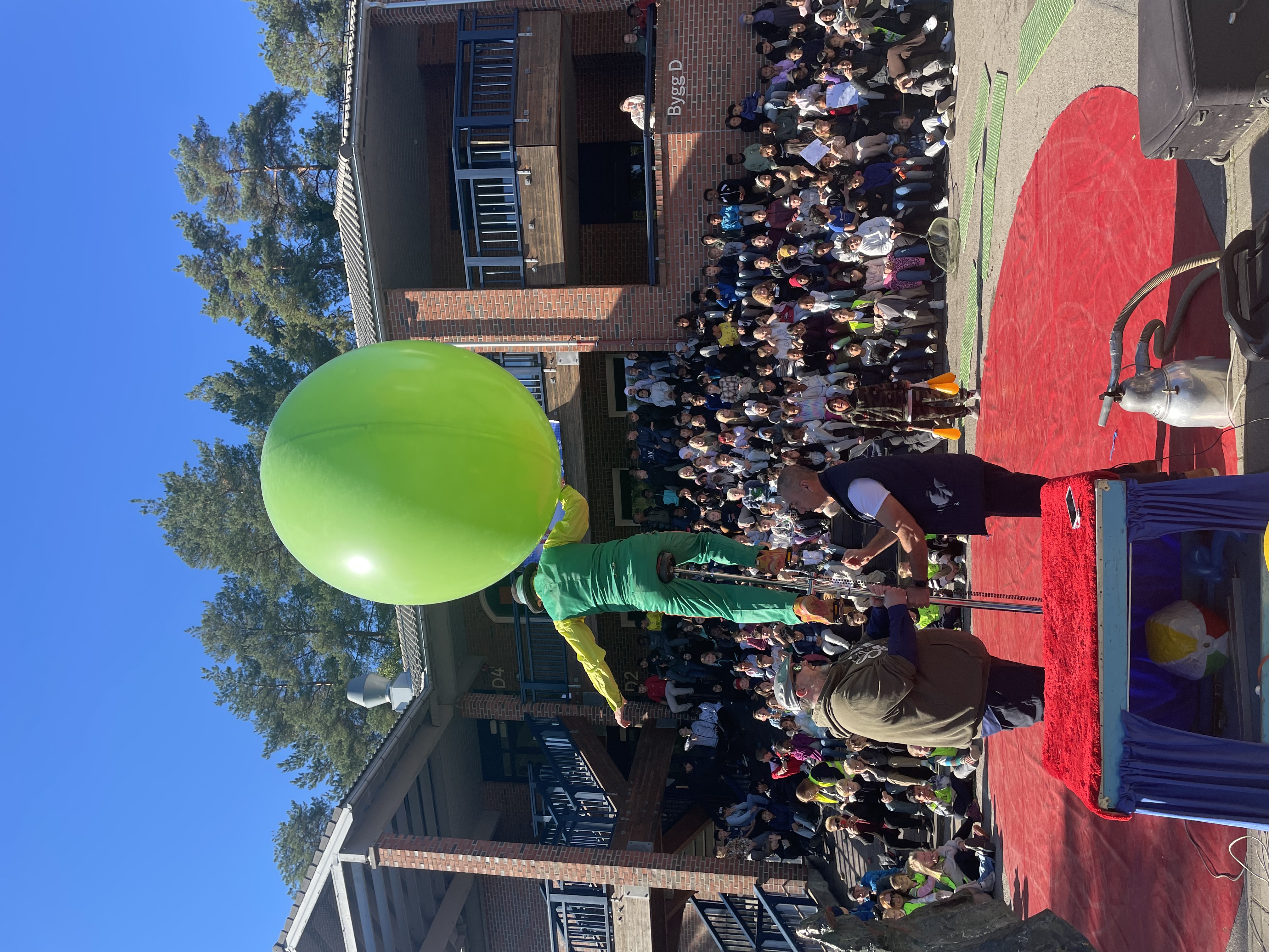 en person som holder en grønn ballong foran en folkemengde