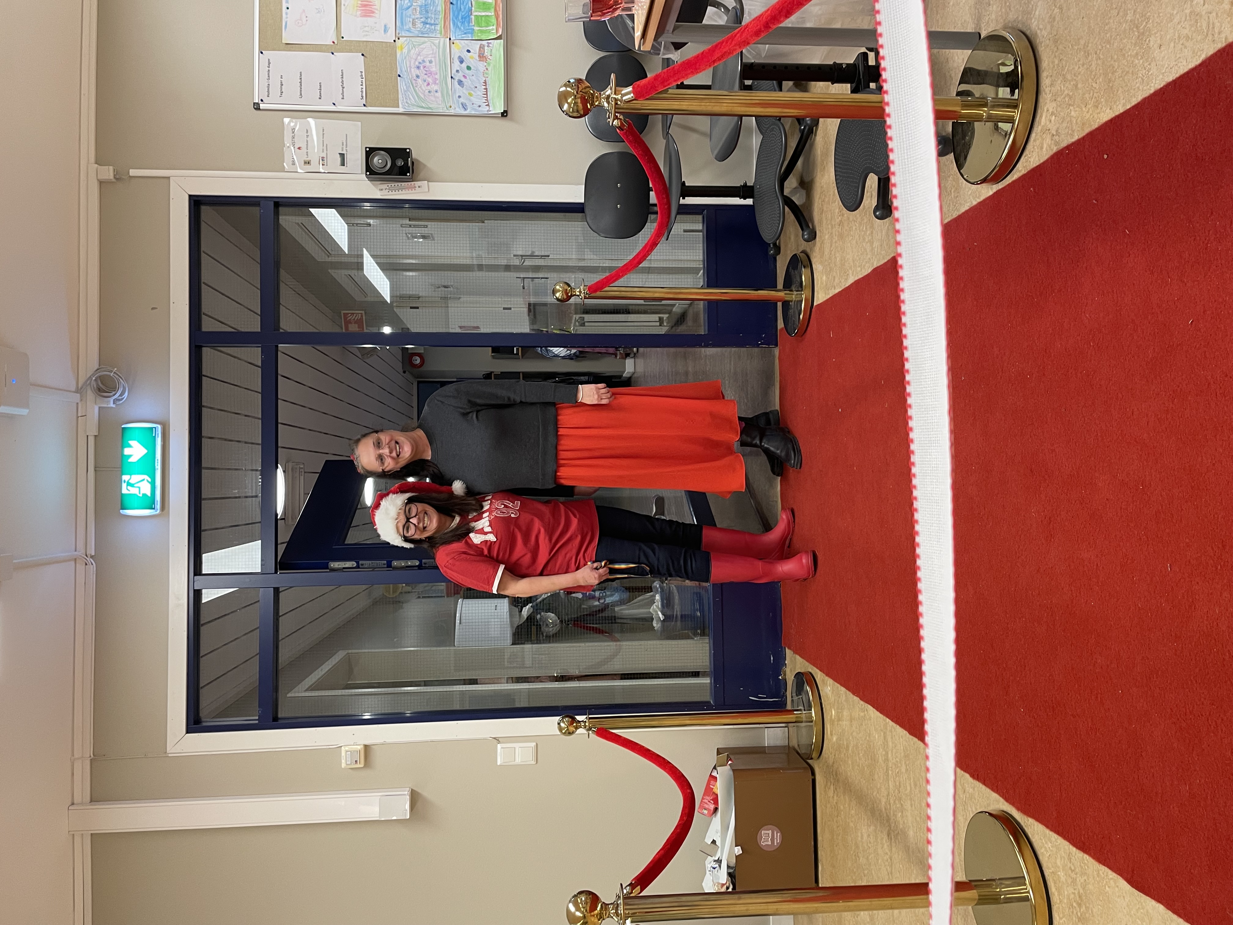 En person og en person står foran en dør med rød løper