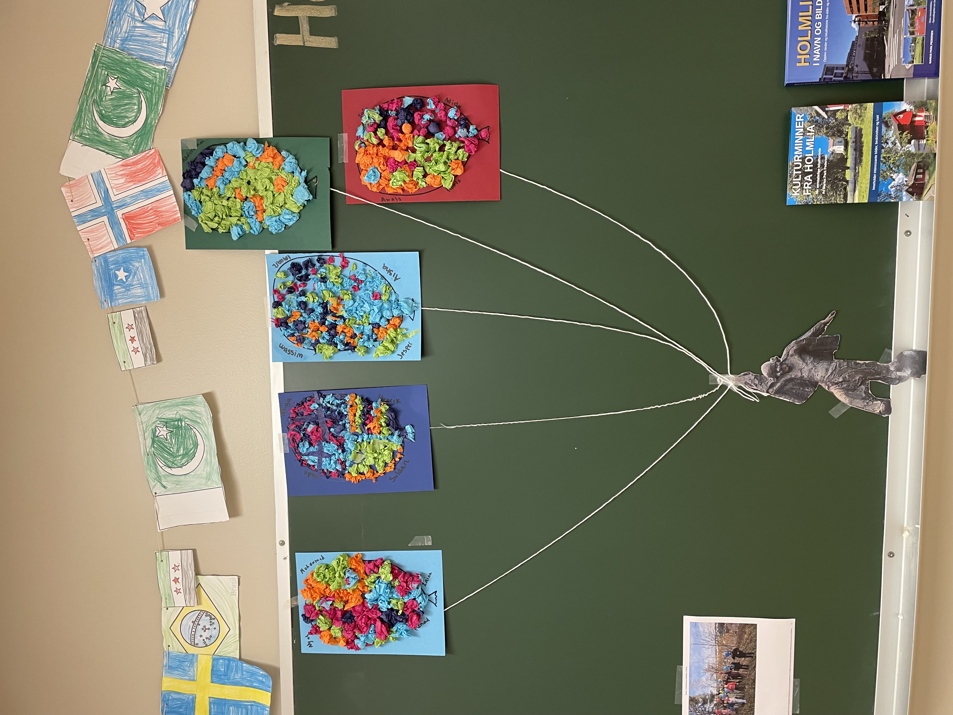 en grønn vegg med en grønn tavle med fargerike flagg og en statue