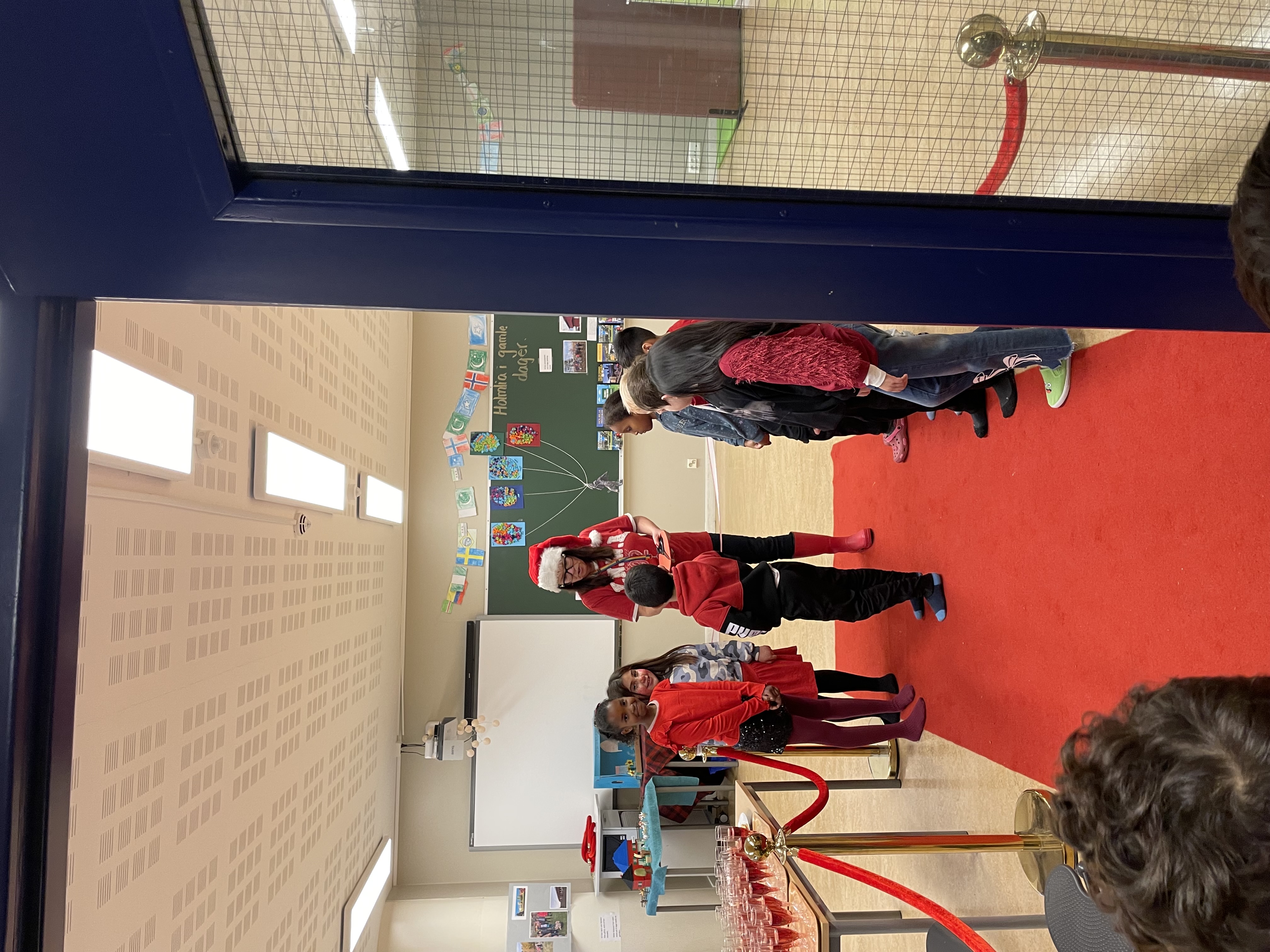 en gruppe mennesker som står i et rom med rød løper